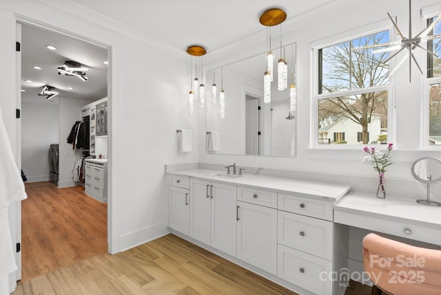 bathroom featuring wood finished floors, vanity, baseboards, washer / dryer, and crown molding