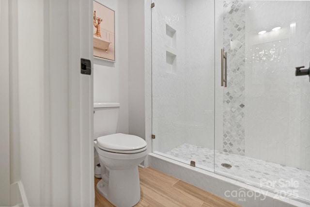 bathroom featuring a stall shower, toilet, and wood finished floors