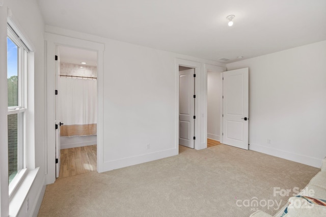 unfurnished bedroom with ensuite bathroom, carpet floors, and baseboards