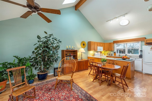 dining space featuring a skylight, beam ceiling, high vaulted ceiling, and light wood-style floors