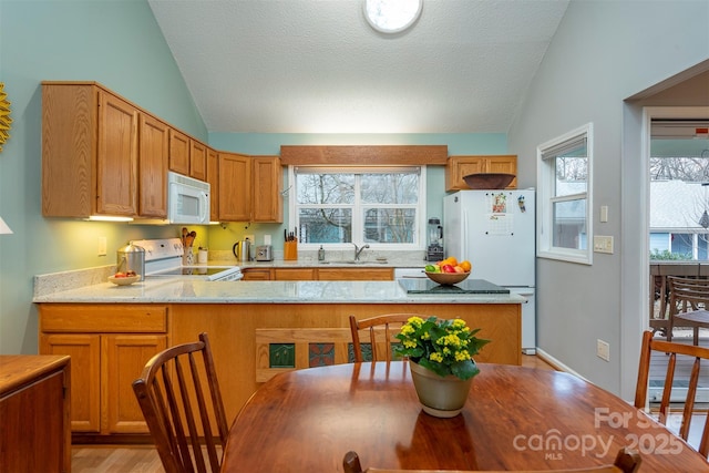 kitchen featuring lofted ceiling, white appliances, a sink, and a textured ceiling