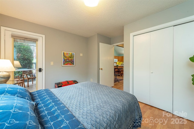 bedroom with light wood-style floors, a textured ceiling, and a closet