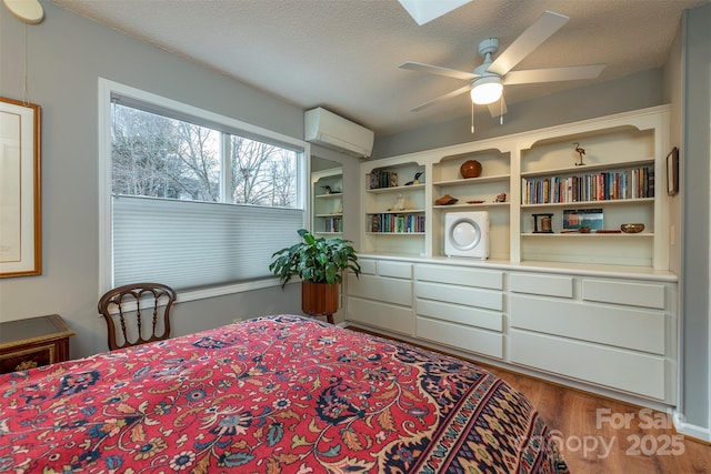 bedroom with a wall mounted air conditioner, a textured ceiling, and wood finished floors