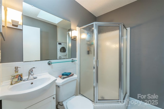 full bath featuring a textured ceiling, toilet, vanity, tasteful backsplash, and a stall shower