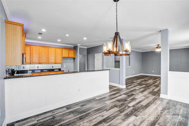 kitchen with dark wood finished floors, dark countertops, crown molding, and decorative backsplash