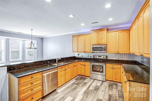 kitchen featuring visible vents, ornamental molding, appliances with stainless steel finishes, a peninsula, and a sink