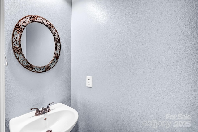 bathroom with a textured wall and a sink