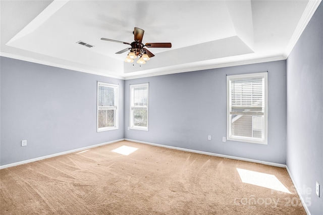 carpeted empty room with baseboards, a raised ceiling, a ceiling fan, and crown molding