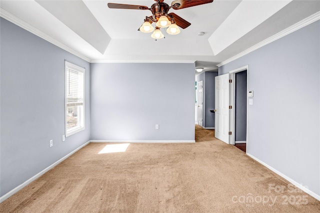 spare room with a raised ceiling, crown molding, baseboards, and carpet floors