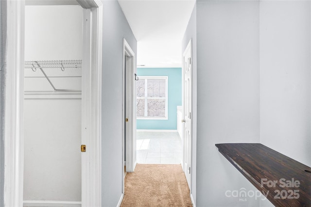 corridor featuring baseboards and carpet floors