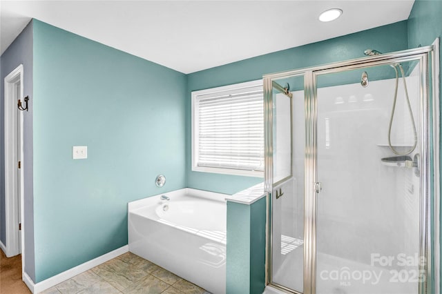 bathroom with a garden tub, baseboards, and a stall shower