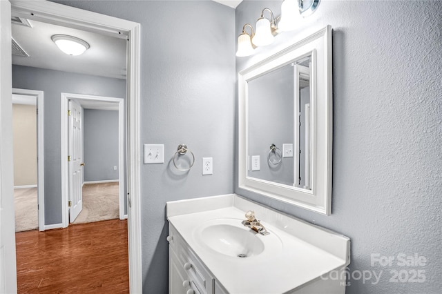 bathroom featuring vanity, wood finished floors, visible vents, and baseboards