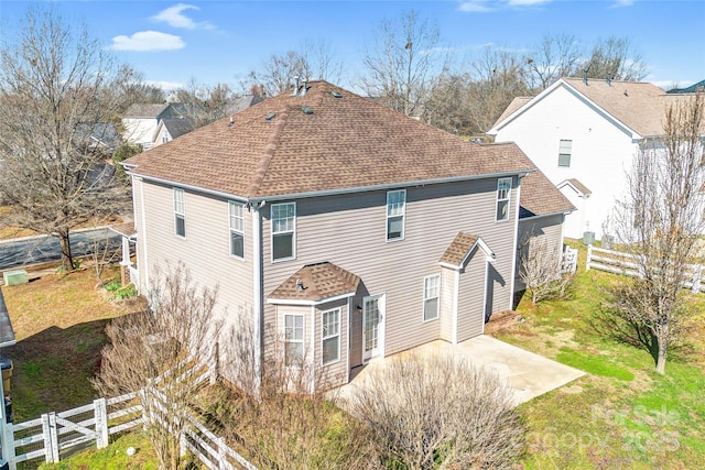 back of property with a patio, a lawn, fence, and a shingled roof