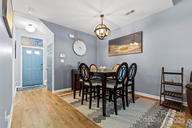 dining space with a chandelier, baseboards, visible vents, and hardwood / wood-style floors