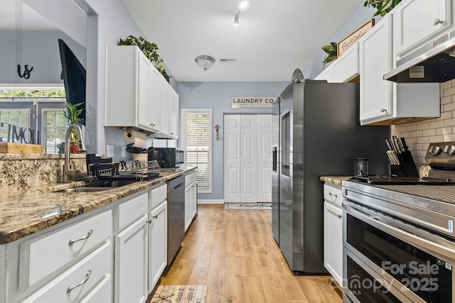 kitchen with stainless steel appliances, a sink, white cabinets, and under cabinet range hood