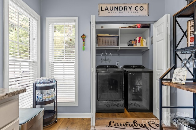 laundry area with baseboards, laundry area, wood finished floors, and washer and dryer