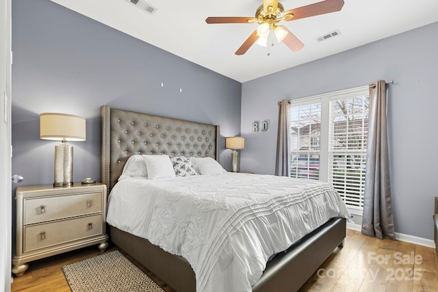 bedroom featuring visible vents, ceiling fan, baseboards, and wood finished floors