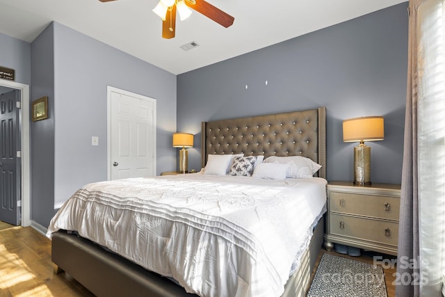 bedroom featuring a ceiling fan, baseboards, visible vents, and wood finished floors