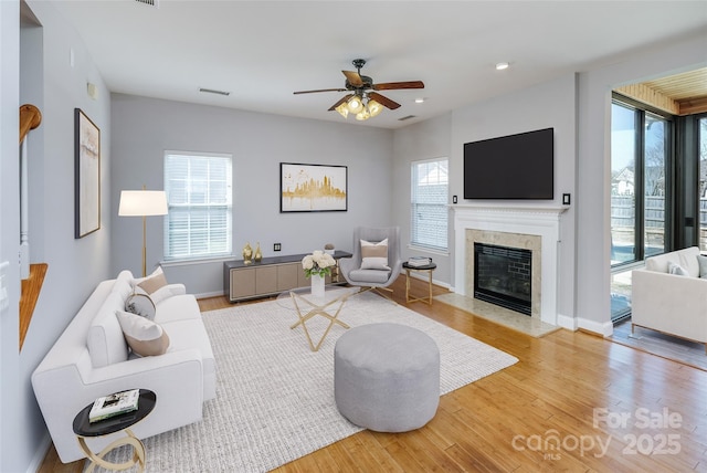 living area featuring a fireplace, wood finished floors, visible vents, and baseboards