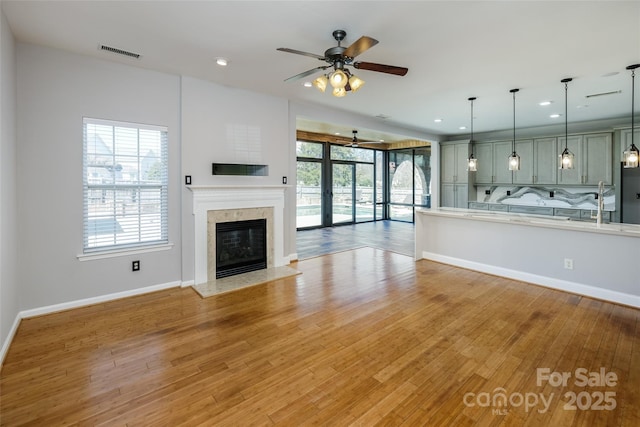 unfurnished living room with light wood-style flooring, a fireplace, visible vents, and baseboards