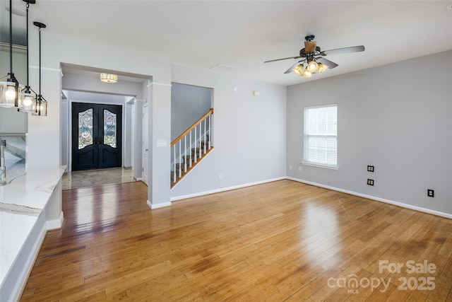 foyer featuring light wood finished floors, stairway, and baseboards