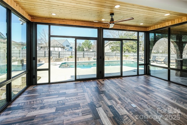 unfurnished sunroom featuring a ceiling fan, wooden ceiling, and plenty of natural light