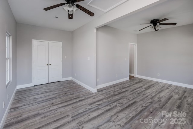 empty room with ceiling fan, wood finished floors, and baseboards