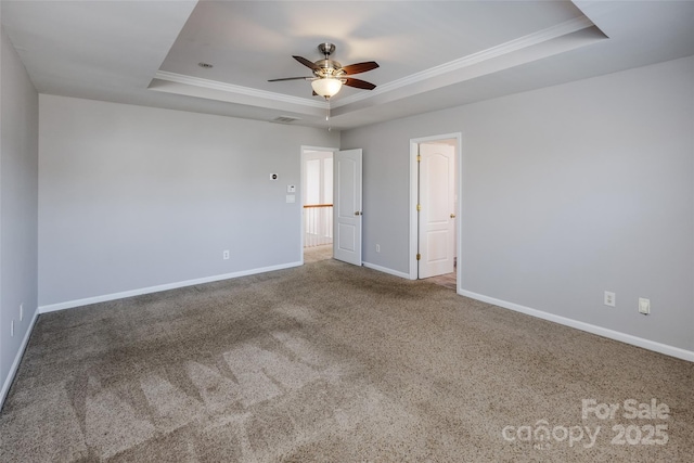 carpeted empty room featuring a tray ceiling, visible vents, crown molding, and baseboards