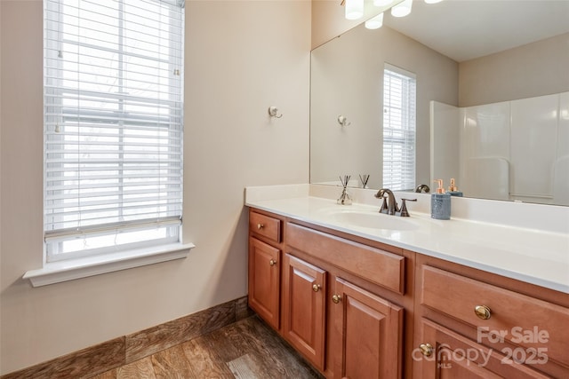 full bath with baseboards, vanity, and a healthy amount of sunlight