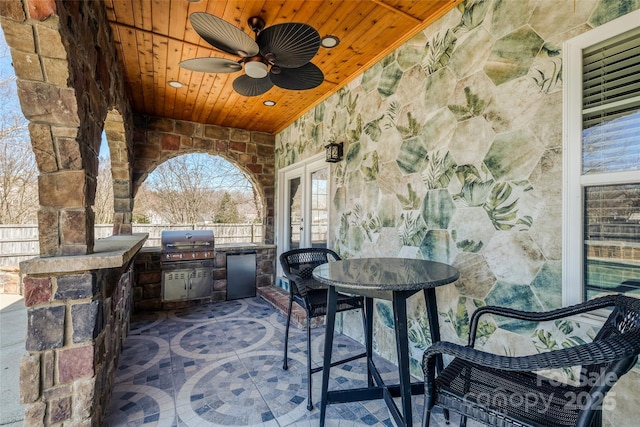 view of patio / terrace featuring french doors, grilling area, outdoor dining space, fence, and exterior kitchen