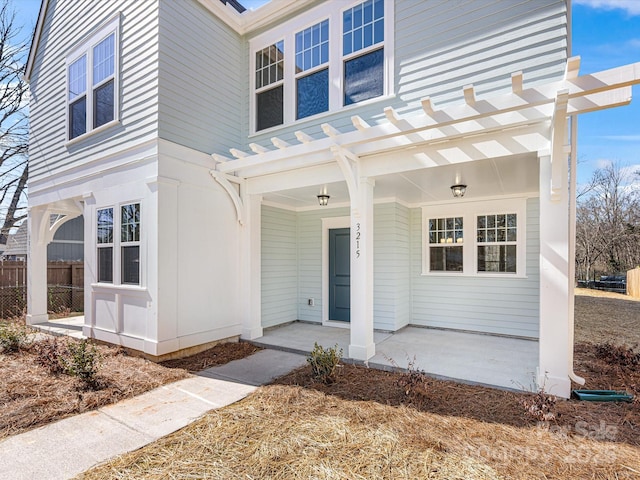 doorway to property with covered porch, fence, and a pergola