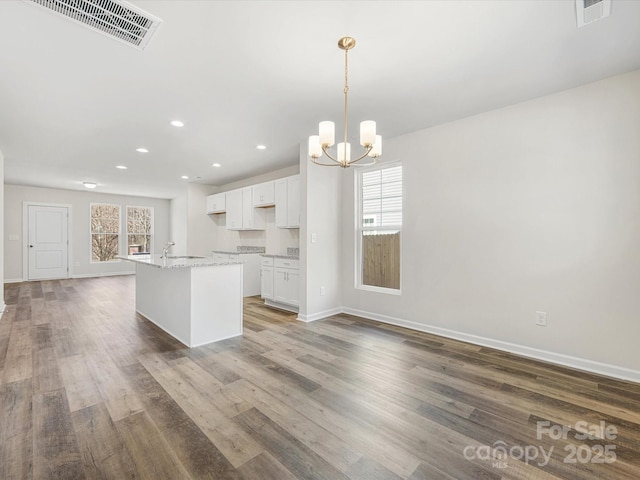 kitchen featuring white cabinetry, a kitchen island with sink, visible vents, and wood finished floors