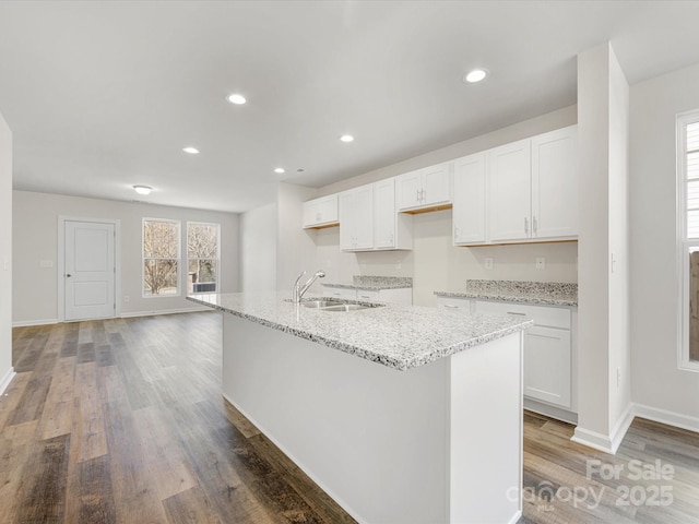 kitchen featuring light stone countertops, light wood-style floors, white cabinetry, a sink, and recessed lighting