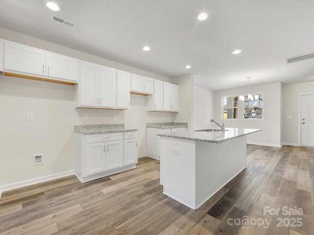 kitchen featuring visible vents, a sink, light wood-style flooring, and white cabinetry