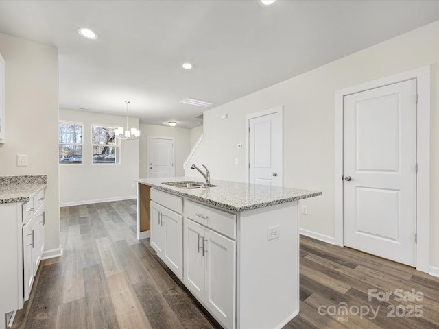 kitchen featuring dark wood-type flooring, a sink, light stone countertops, and white cabinets