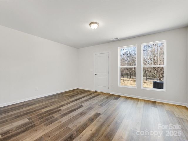 empty room featuring visible vents, baseboards, and wood finished floors