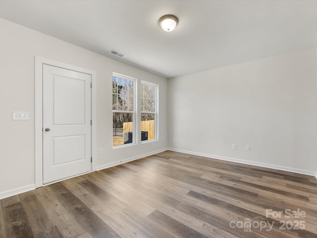 spare room with visible vents, baseboards, and wood finished floors