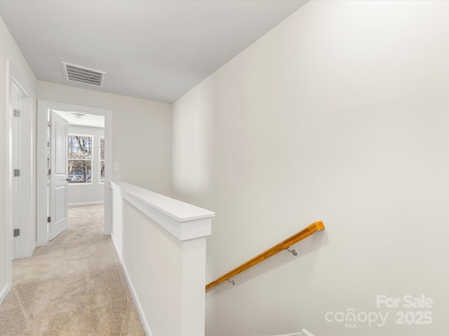 hall with visible vents, light carpet, an upstairs landing, and baseboards