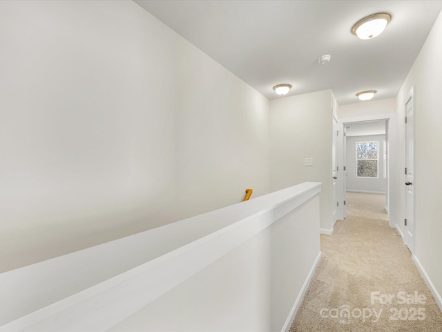 corridor with an upstairs landing, light colored carpet, and baseboards