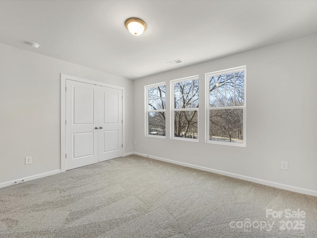 unfurnished bedroom with a closet, carpet flooring, visible vents, and baseboards