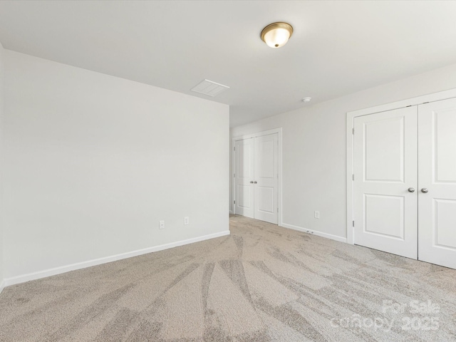 unfurnished bedroom featuring carpet, visible vents, baseboards, and multiple closets