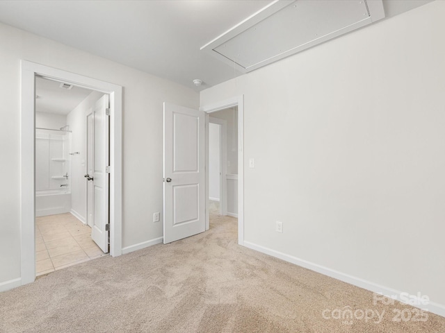 unfurnished bedroom featuring carpet floors, attic access, baseboards, and tile patterned floors