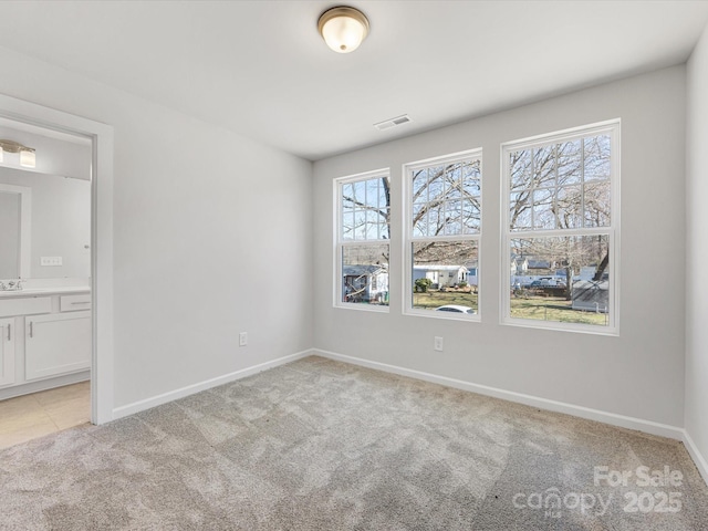 unfurnished bedroom with baseboards, multiple windows, visible vents, and light colored carpet