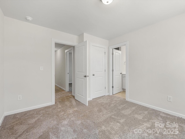 unfurnished bedroom featuring connected bathroom, baseboards, a closet, and light colored carpet