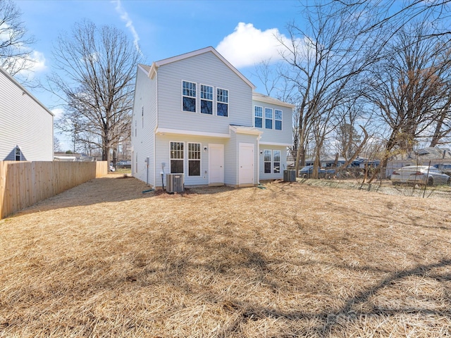 rear view of property featuring a lawn, fence, and central AC