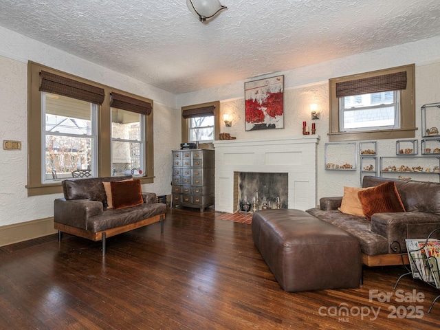 living room featuring a brick fireplace, a textured wall, a textured ceiling, and wood finished floors