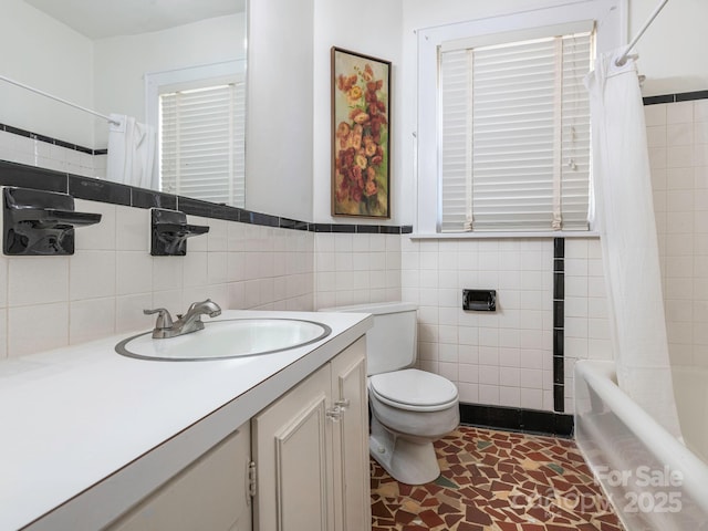 bathroom with toilet, vanity, tile walls, wainscoting, and shower / bath combination with curtain