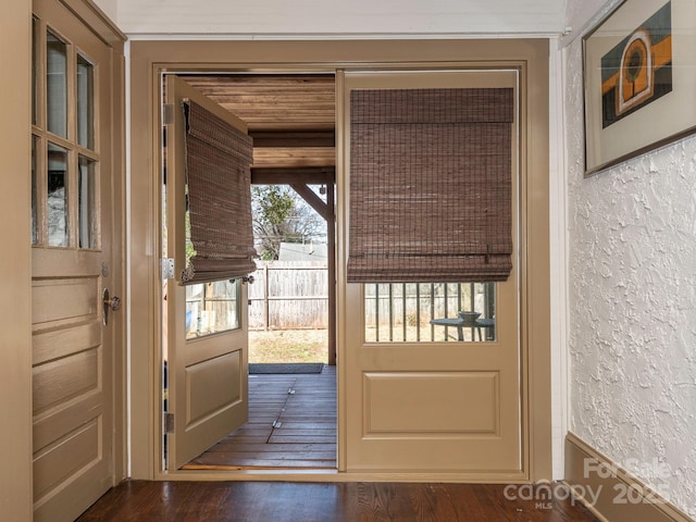 doorway with hardwood / wood-style flooring and a textured wall