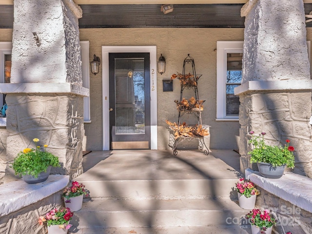 view of exterior entry featuring covered porch and stucco siding