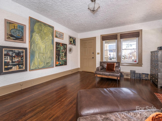 unfurnished room with a textured ceiling, a textured wall, wood finished floors, and baseboards